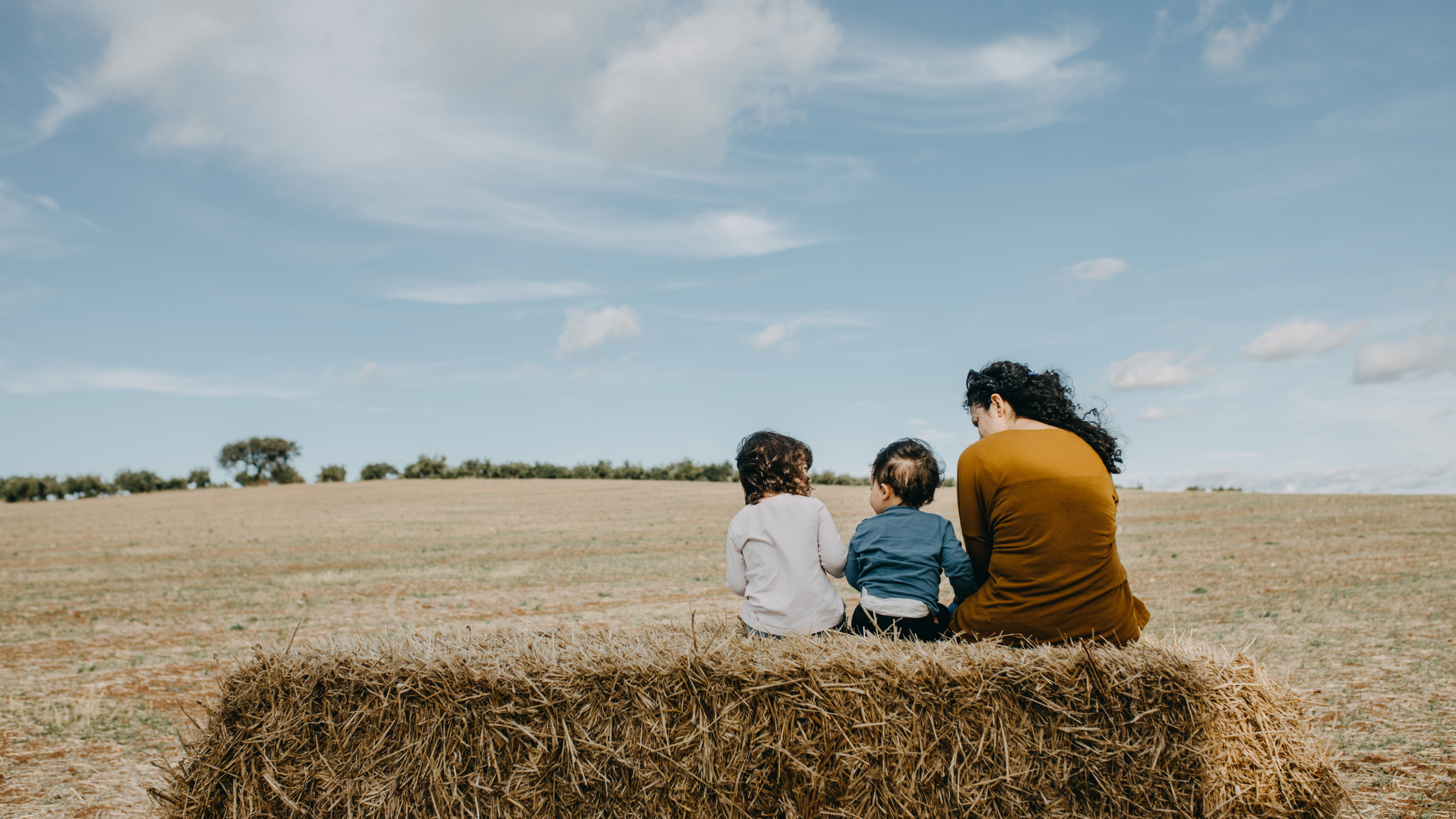 A family sitting together in a field, symbolising connection, growth, and intentional living for a thriving, healthy life.